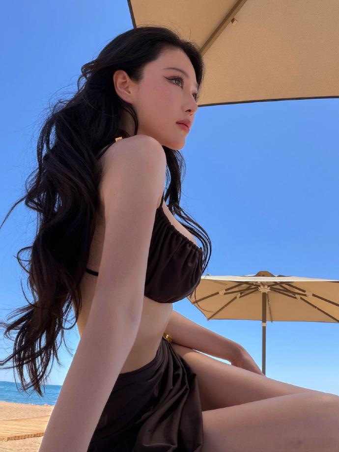 张馨予海边比基尼大片碧海蓝天作背景，张馨予漫步沙滩自在舒展，流畅优越的身材线条一