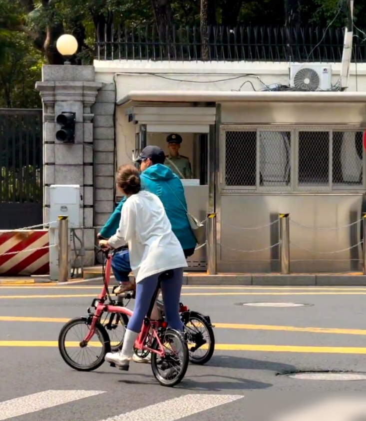 胡歌单手骑车，另一只手死死挡在女儿正脸前，肩上还斜挎着老婆的小包。9月26日，上海衡山路一带，一家三