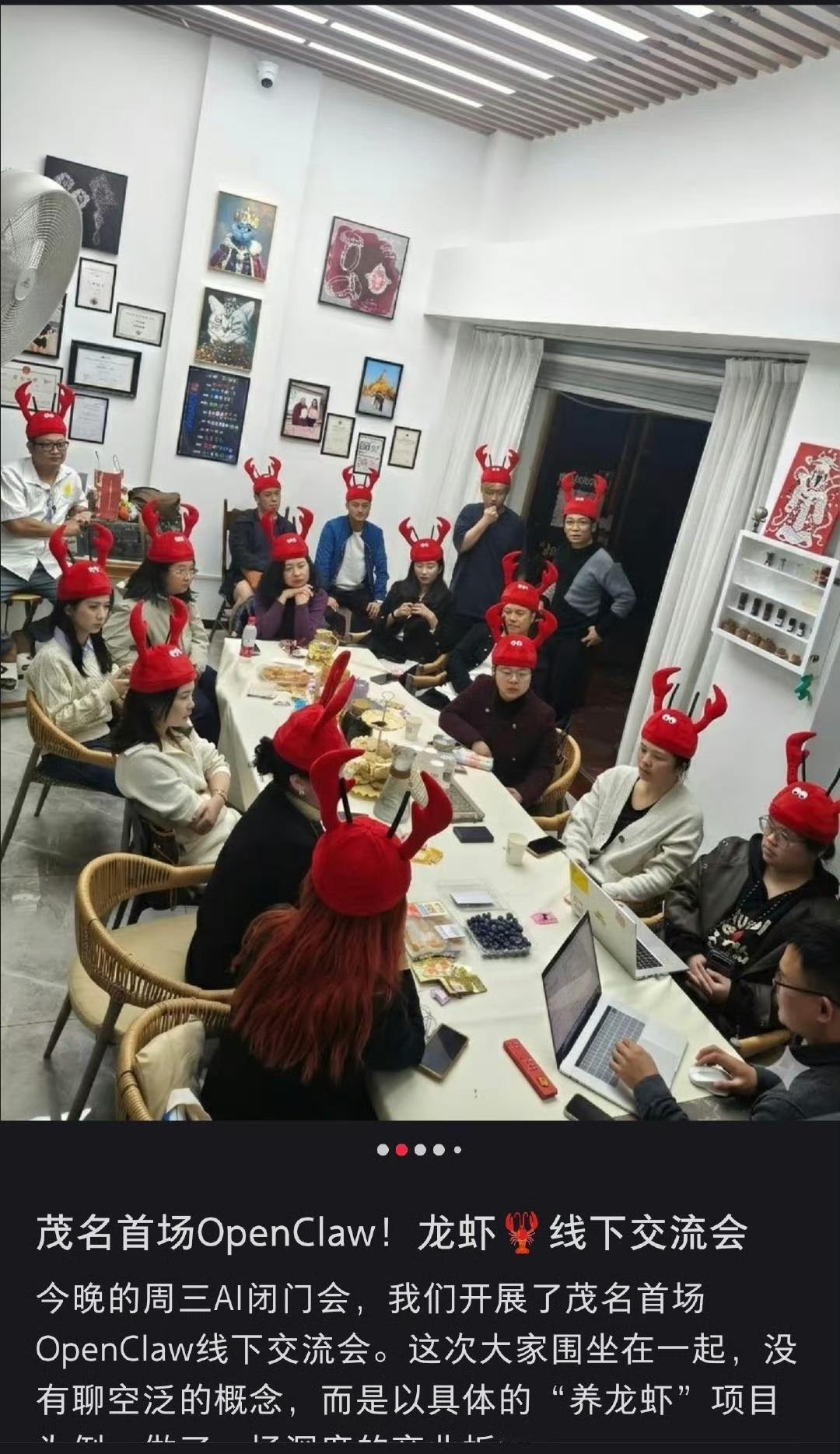 一群人戴着一模一样的红色龙虾帽，围坐在长桌前，桌上摆着零食、电脑。还有人正对