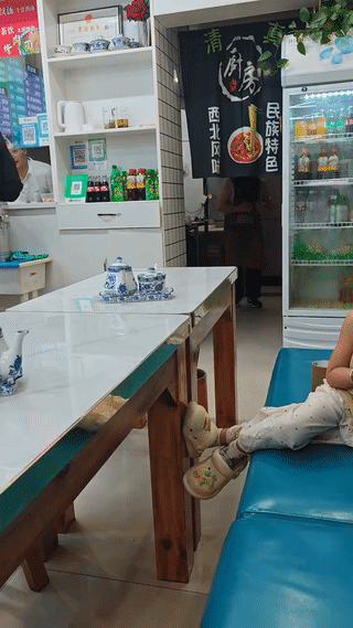 这是一家非常标准的“兰州牛肉面”馆。男主人在厨房里拉面，女主人则在厨房里忙碌。