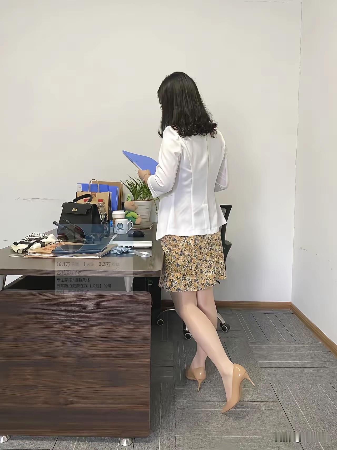 办公室里一位穿裙子的女士在看手机。