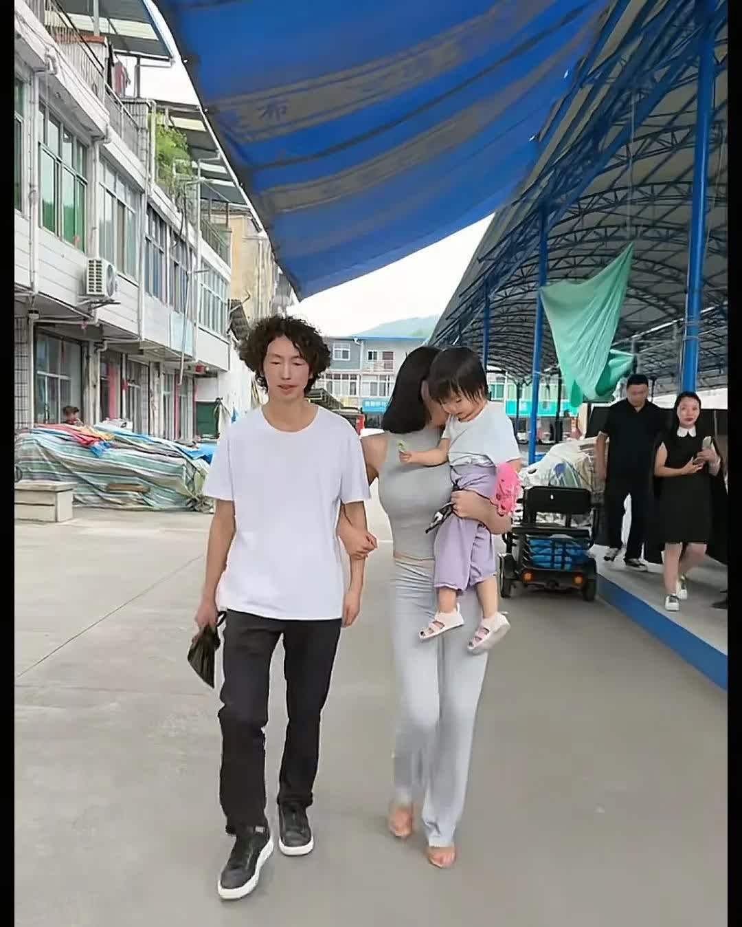 龚玥菲和庞麦郎走在街上，一手挽着庞麦郎的手臂，一手抱着孩子，这是个很坚强女人。
