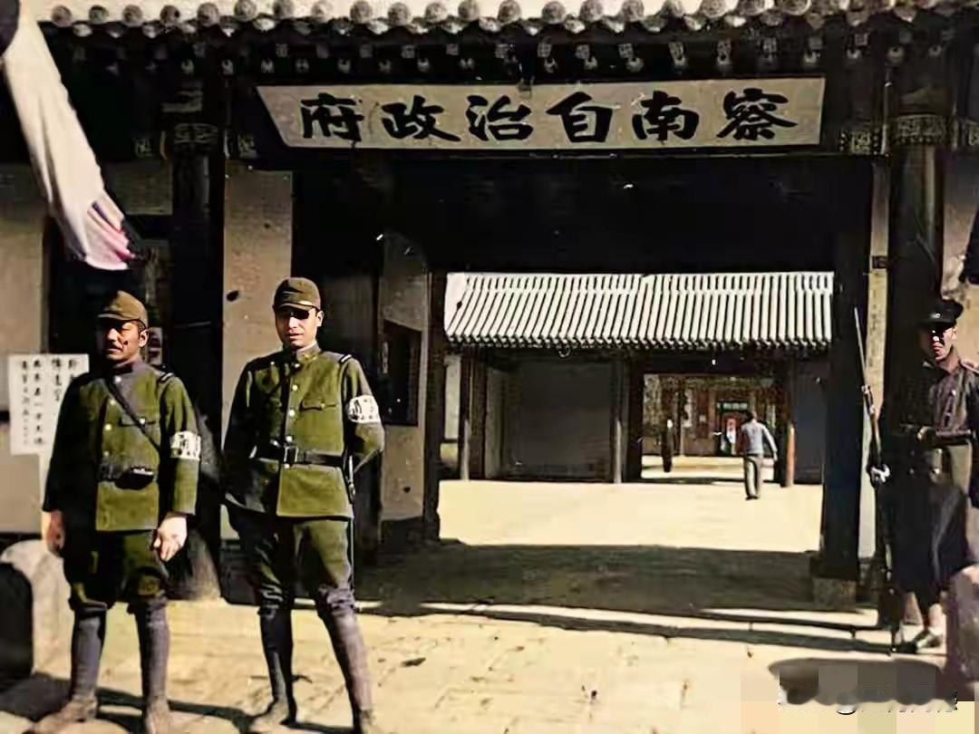 两个日本鬼子站在这个大门前合影留念，大门上有一个牌匾，写着“察南自治政府”六个大
