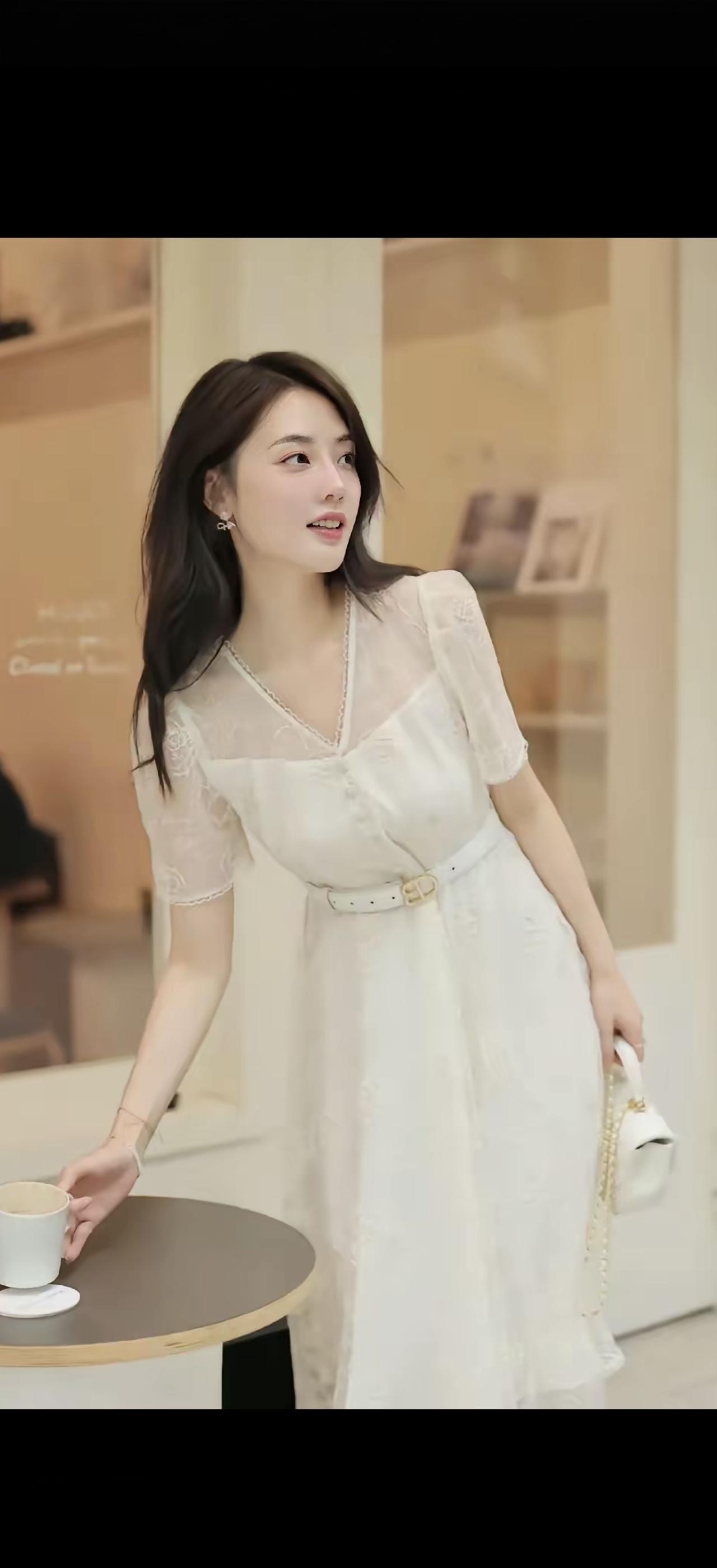 一个穿白裙子的女生在喝咖啡。