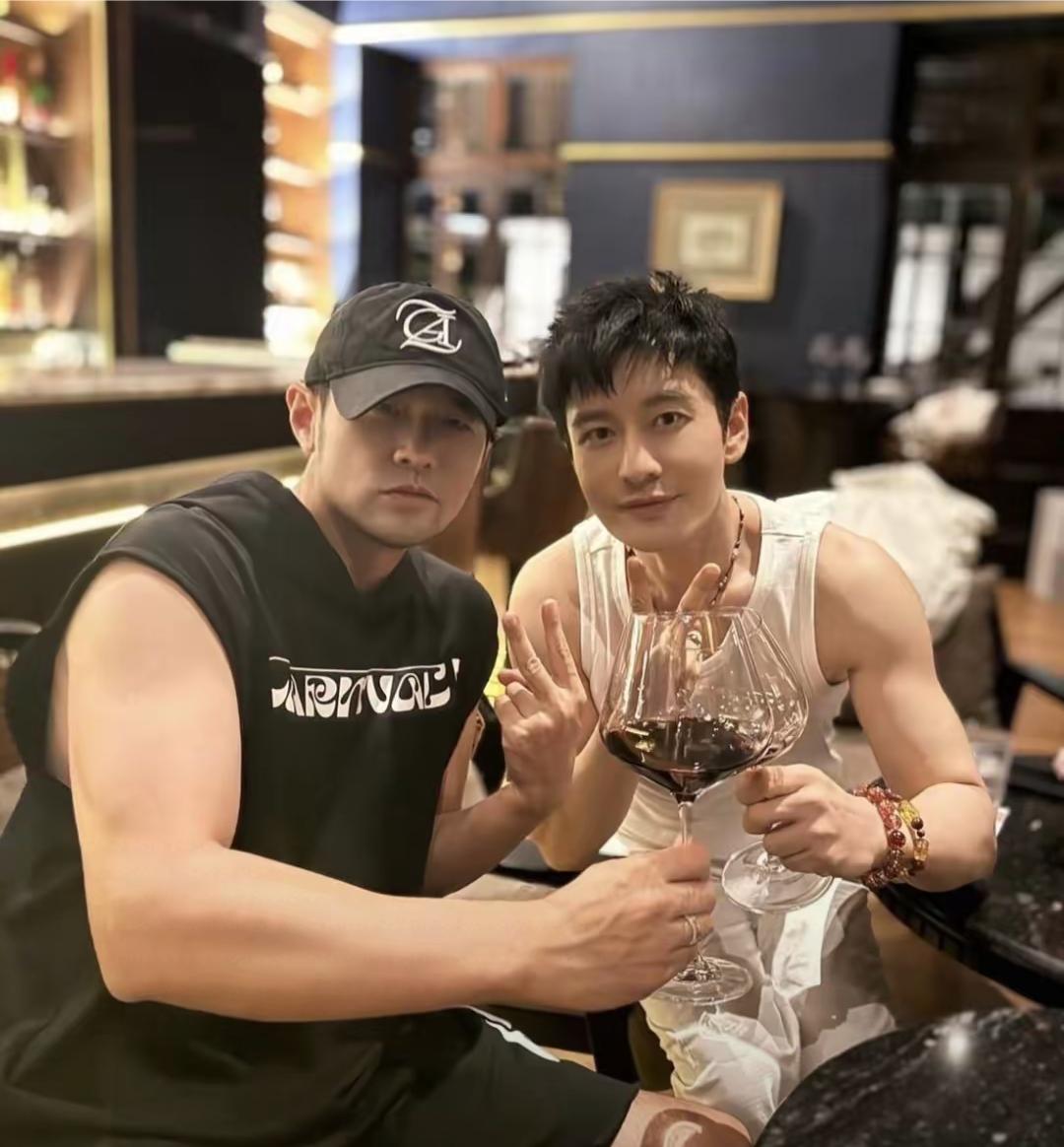 47岁的周杰伦和50岁的黄晓明在泰国一间酒吧聚会，黄晓明穿着白色背心，看得出来，