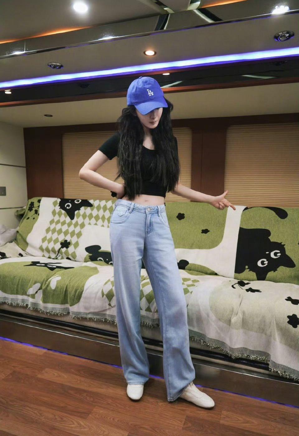 工作间隙偷闲的杨幂，对着沙发上印花小黑猫玩起自娱自乐的小游戏，松弛又可爱的状态，