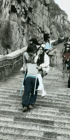 两个女孩爬泰山累的走不动了，就与一名挑夫谈妥价钱让挑夫抱上山，挑夫可能是抱新鲜吧
