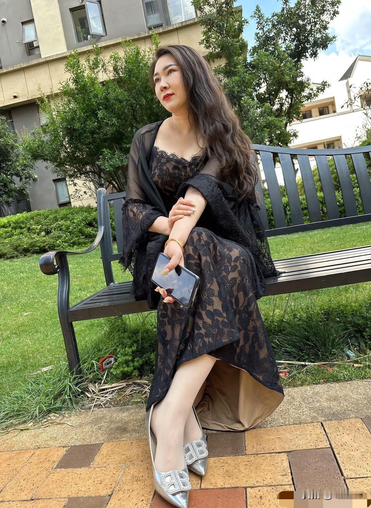 一个女孩坐在公园长椅上，看着手机。