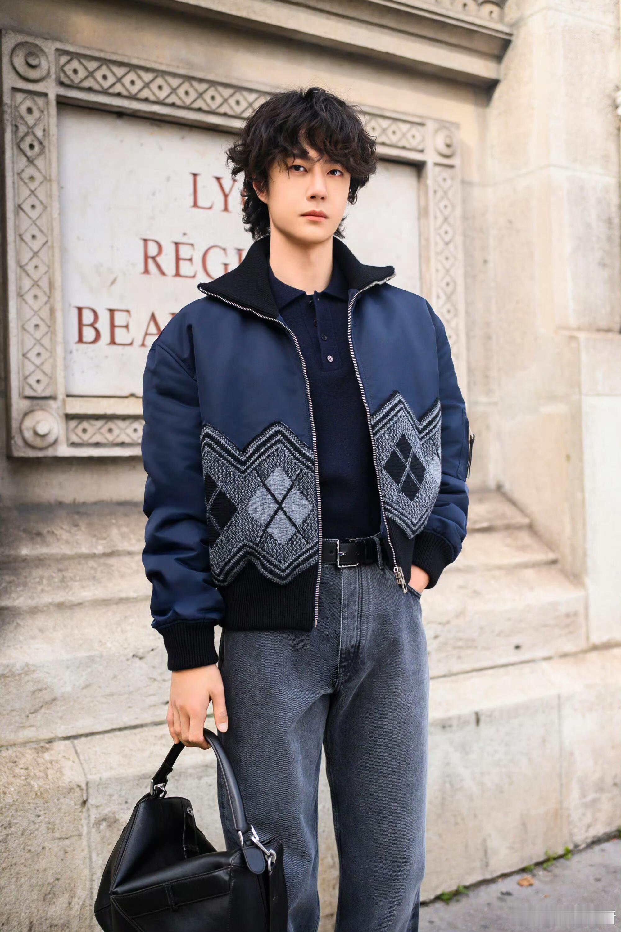 王一博解锁2026早春秀场，藏蓝菱格夹克+灰牛仔裤配羊毛卷，巴黎街头随手拍都是高