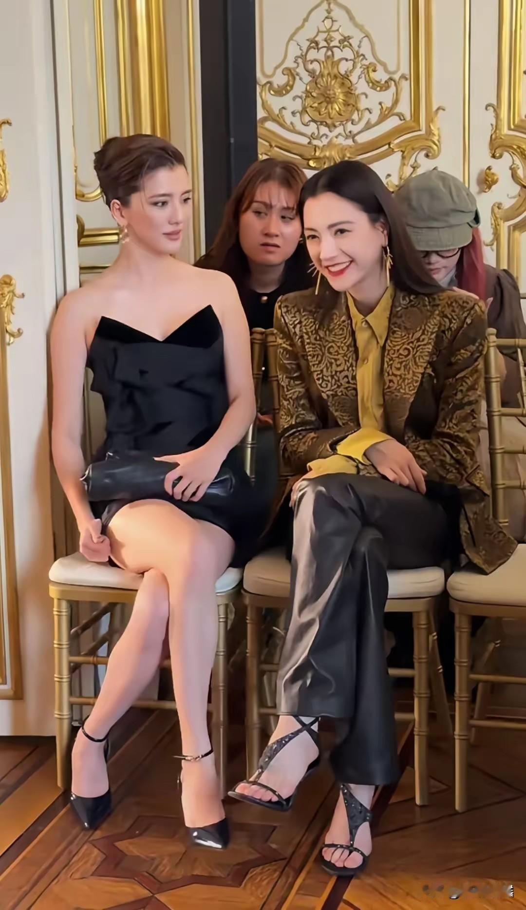 巴黎秀场后台，吴千语和娜然并肩坐在一起，两人近距离交谈，画面格外吸睛。吴千语一袭黑色抹胸短裙，盘发造