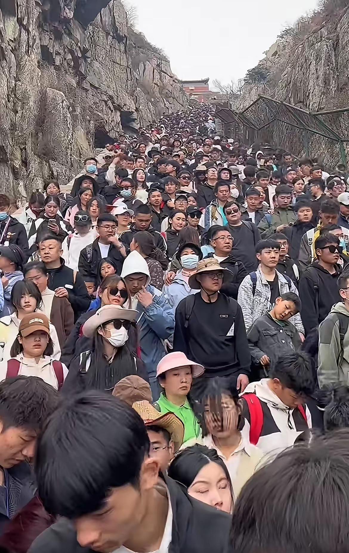这是网友拍的五一假期某地景点游人如织的场景。从山道上挤满游客的脸上，让人看到的