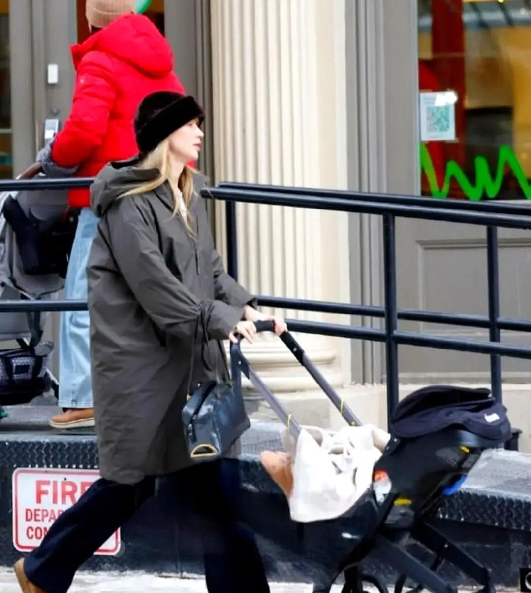 詹妮弗·劳伦斯推着婴儿车走在纽约雪后的上东区，灰绿棉衣裹得严严实实，手里还提着保