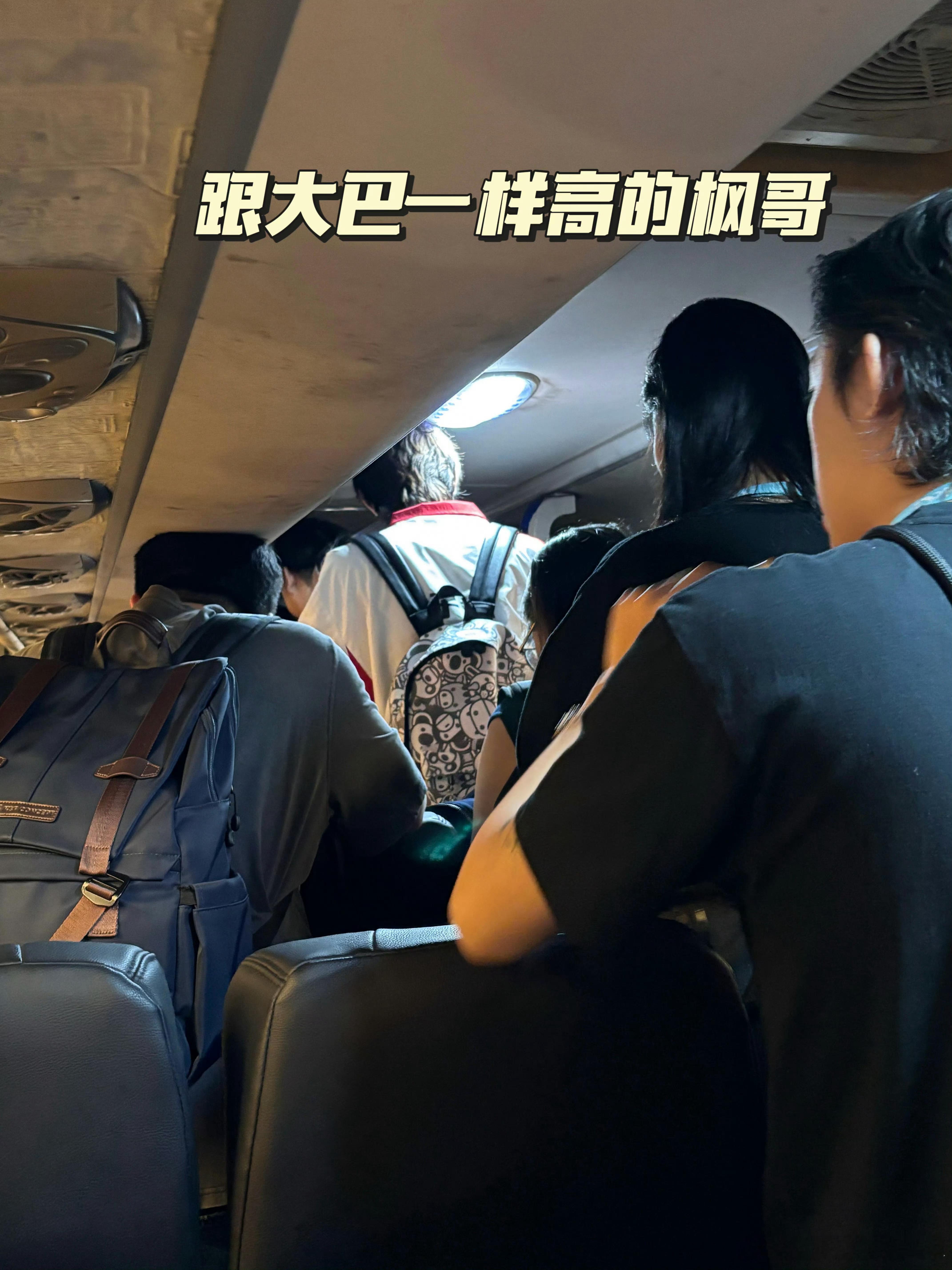 AG子枫ovo190cm身高在大巴内与车顶形成强烈对比，画面显示其需低头行进。