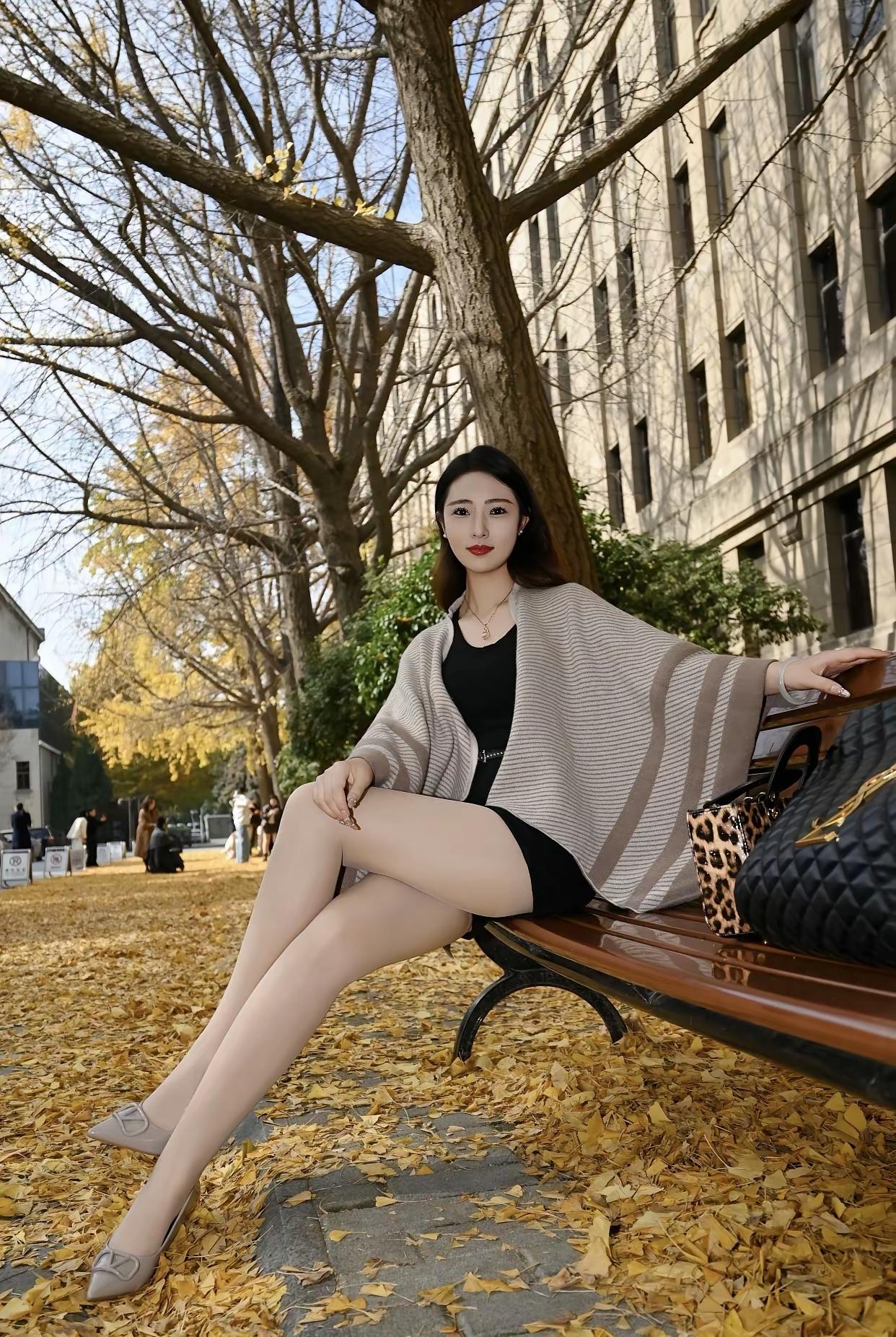 秋日暖阳下，优雅的女孩坐在长椅上，享受着落叶的浪漫