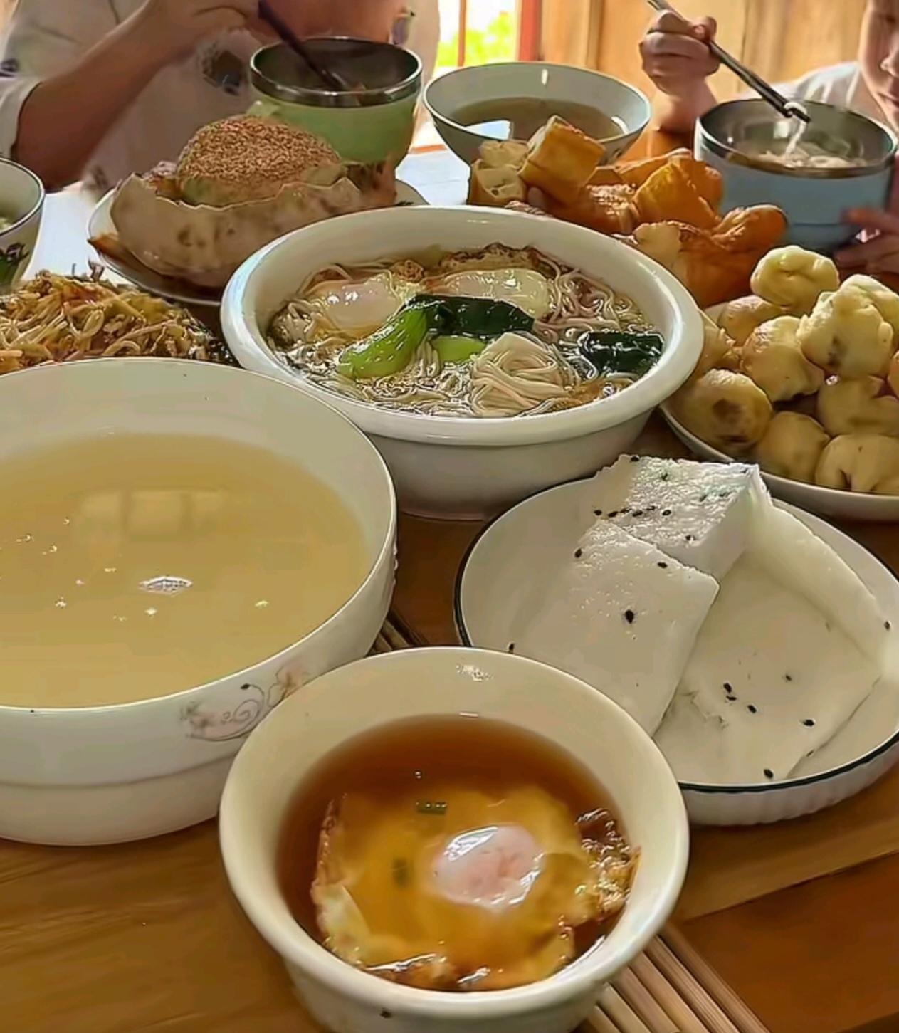 大姑家六口人的早餐摆了满满一桌，面条、炒粉、油条、小包子、甜芝麻饼、米发糕。