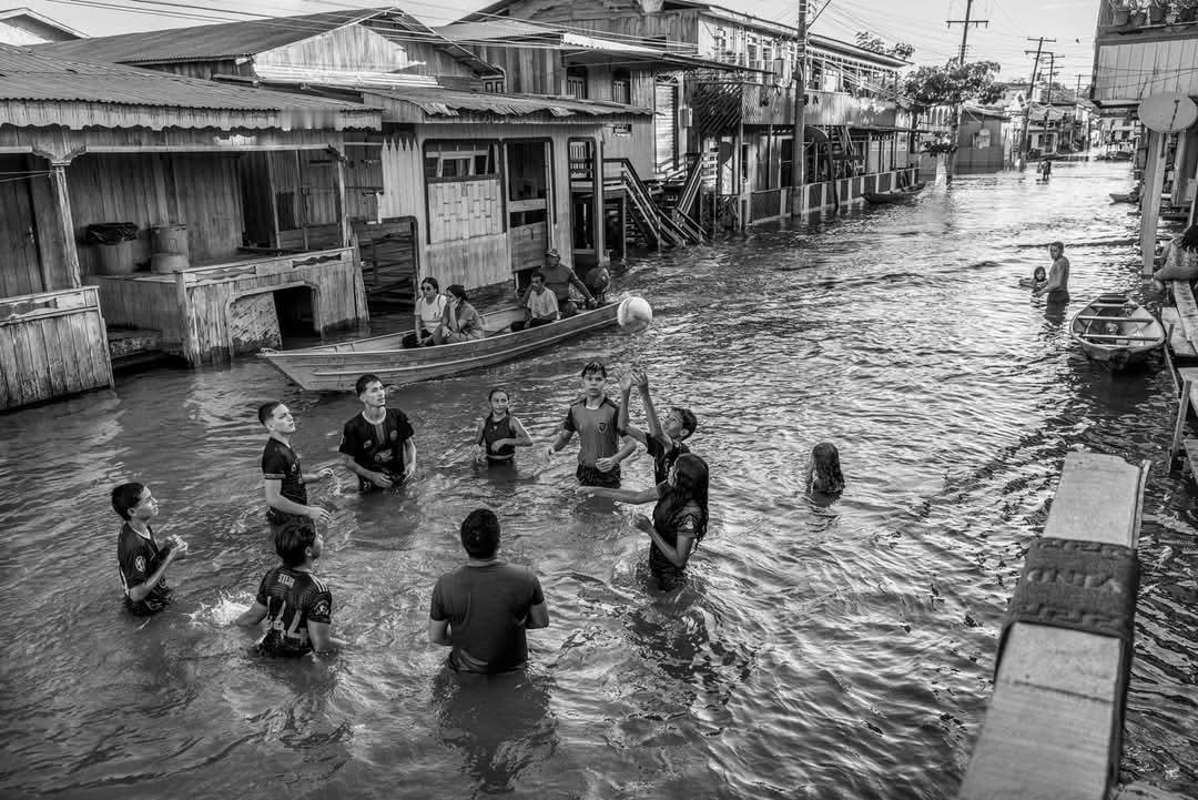 画面中，亚马逊河泛滥平原上的小镇阿纳芒（Anamã）的居民在及腰深的水中打排球，