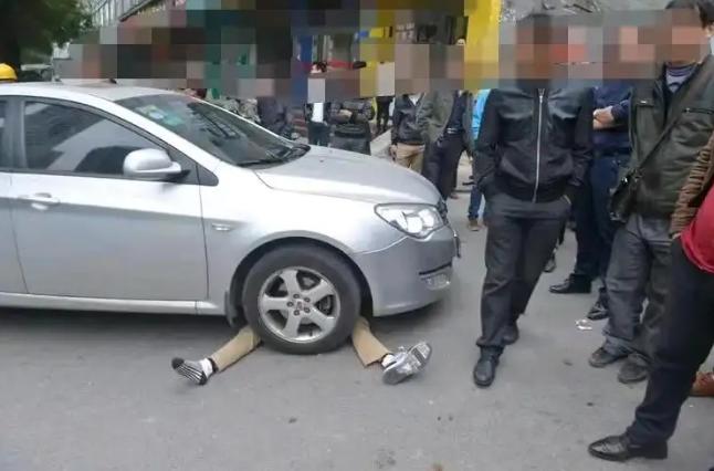 沈阳女子等红灯时无聊玩手机，没有看到大妈躺在她车跟前碰瓷。绿灯后女子启动车辆，不