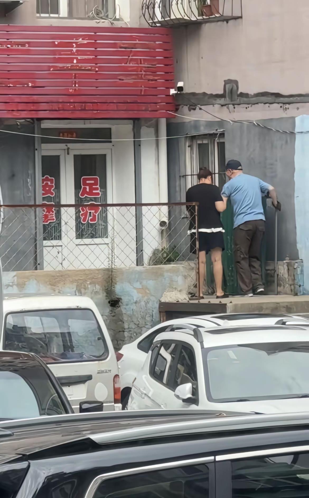 两人在修门，旁边停着几辆车。