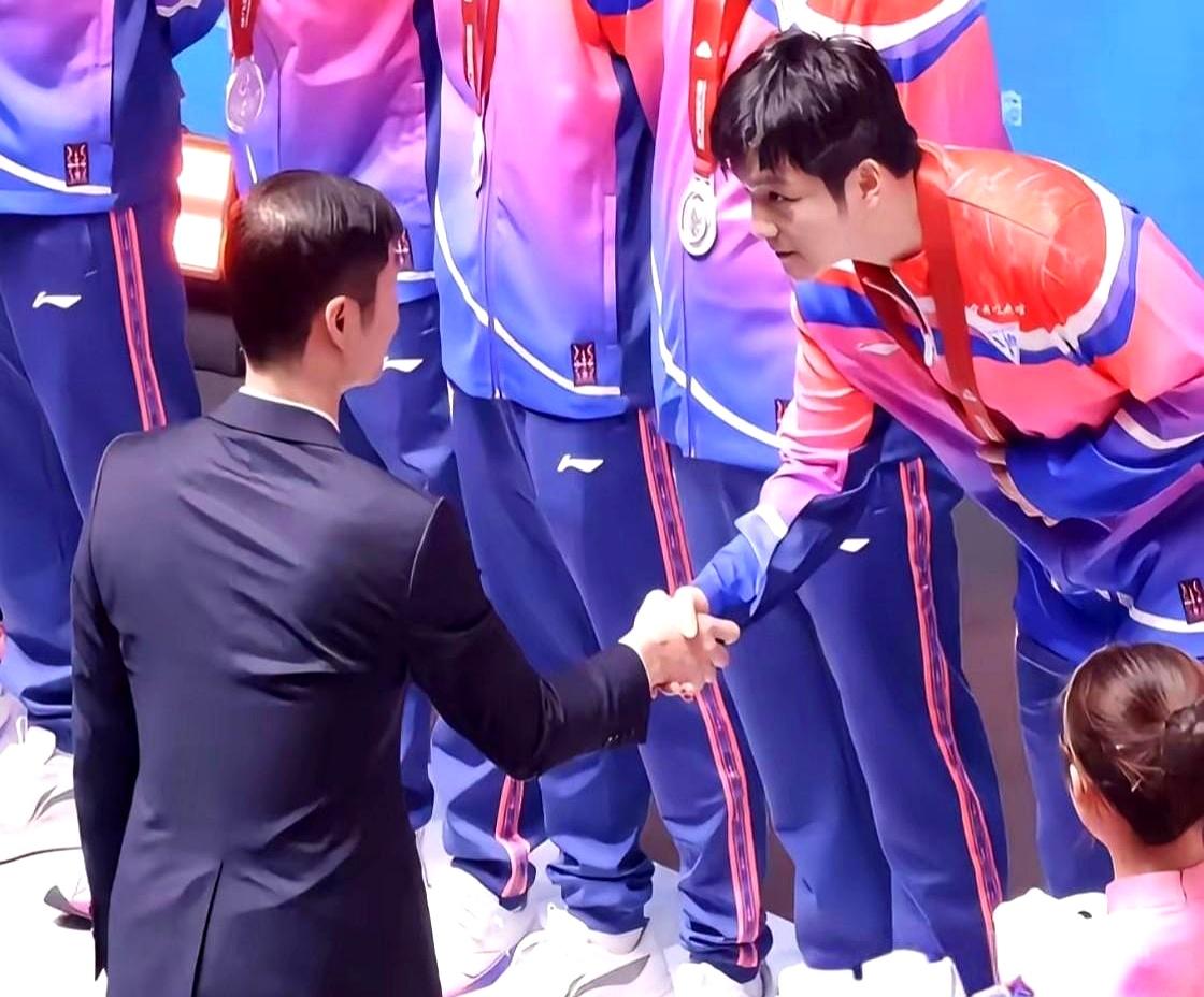 樊振东握手礼仪与众不同，展现出个人素养。王励勤走到跟前发吉祥物，樊振东那