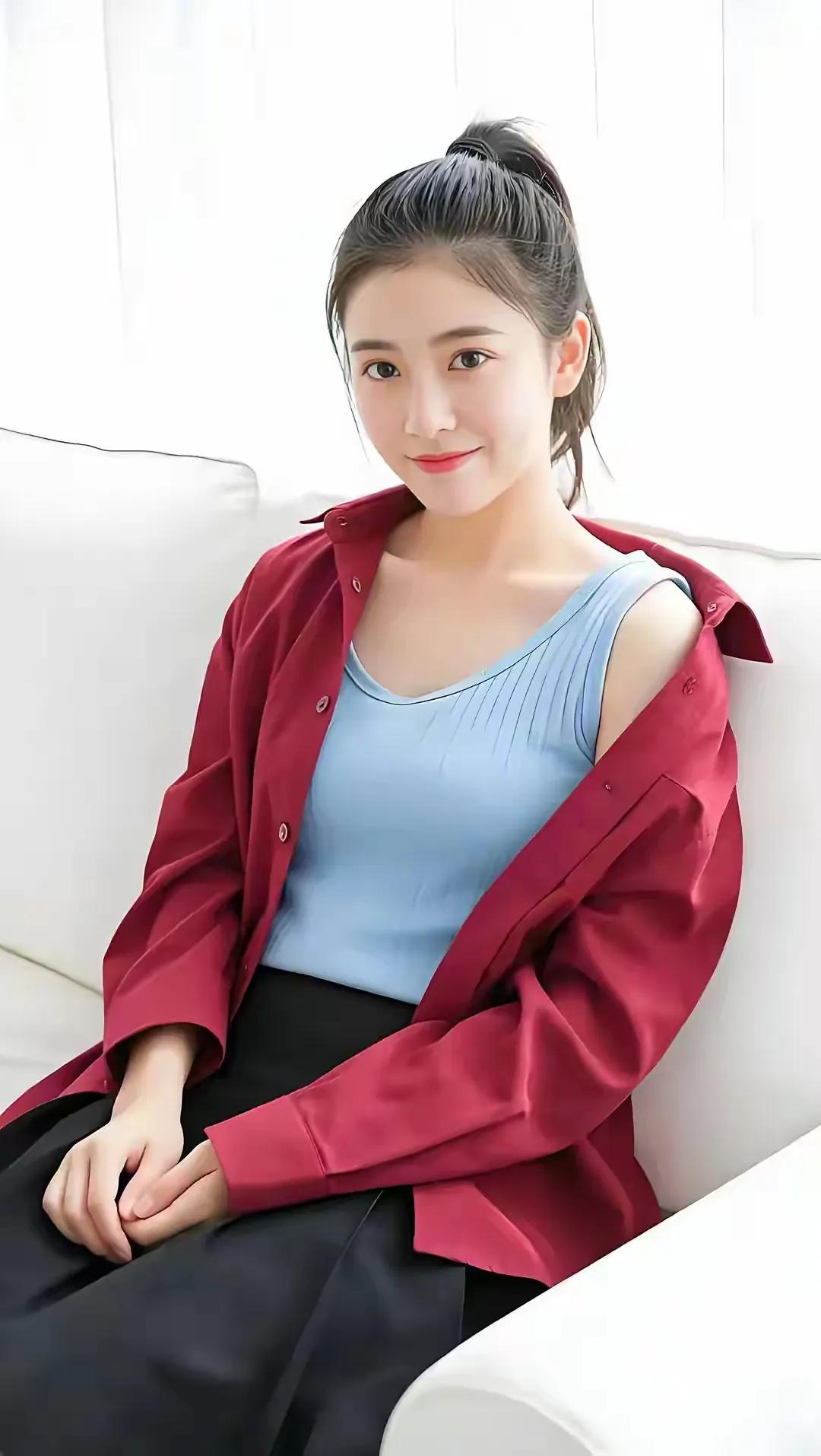 优雅红衣少女，温柔微笑，坐于白色沙发上。