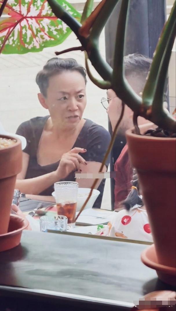 路人镜头下宋丹丹身着简约黑色低领短袖，头发扎个小揪揪，素颜状态，指甲涂红甲油，十