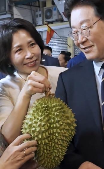 李在明在越南街头吃榴莲；4月23日韩国总统在越南逛街时买了一个榴莲，然后和夫人一