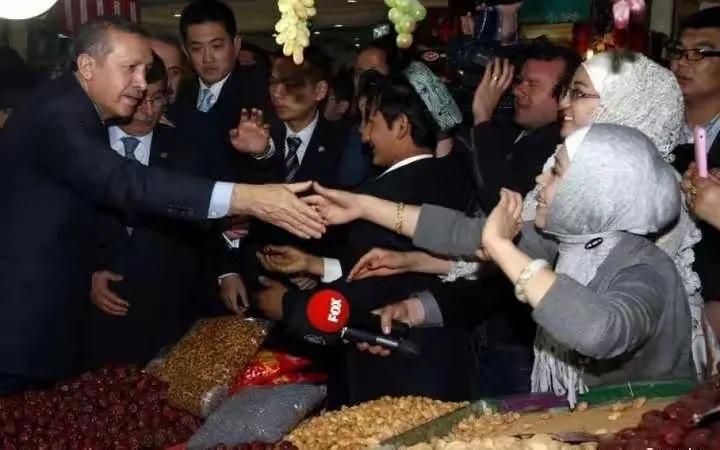 这是土耳其总统埃尔多安在我国西域访问的相片。他跟我国西域的包头巾女人握手。朱拉