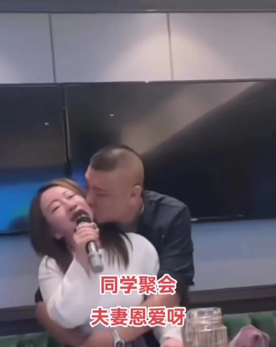 唱歌的女人被一个S迷迷的男人紧紧搂着腰，男子忽儿亲女子的脸，忽儿亲女子的耳朵，女