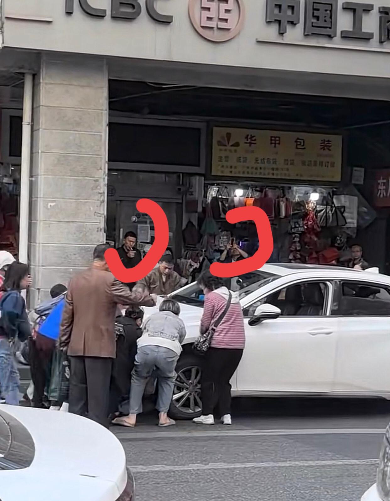 广州一德路，一辆白色小车，男司机靠边停车时不慎将一名路人压在车底。这时，附近一群