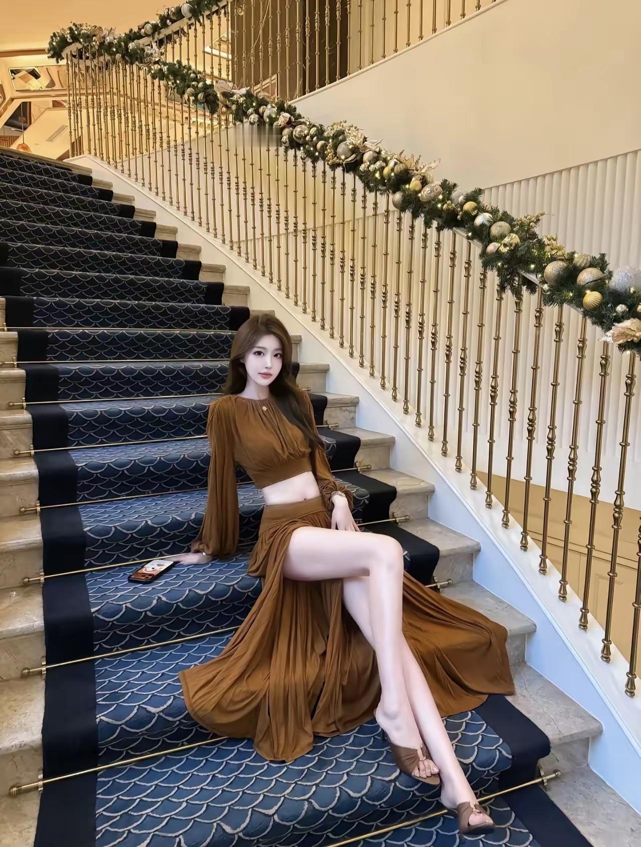 优雅楼梯上的时尚穿搭，棕色长裙与金色扶手相得益彰。