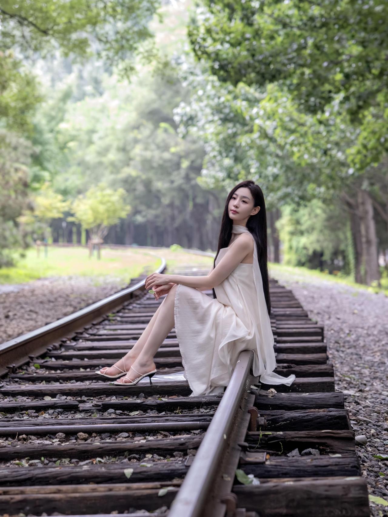 美到骨子里的女人，是什么样子的草木幽深，铁轨蜿蜒，透明雨伞隔绝俗世喧嚣，一袭白裙
