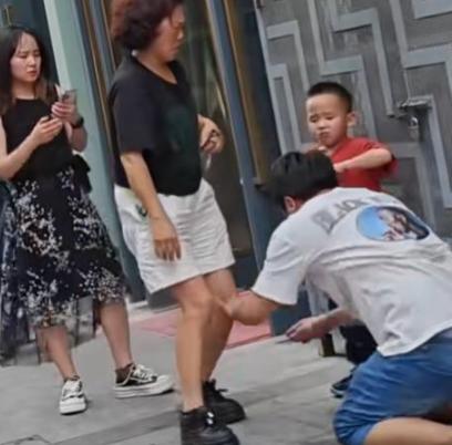 街头，一男子跪在水泥地上，向劈腿老婆连磕三个响头，哭喊：“我一天打两份工，从早