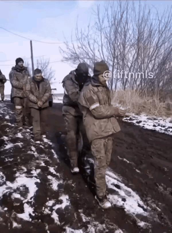 一个个乌军士兵被绑住双手排着一排前往俄罗斯的战俘营之中，这些被俘虏的乌军士兵都是