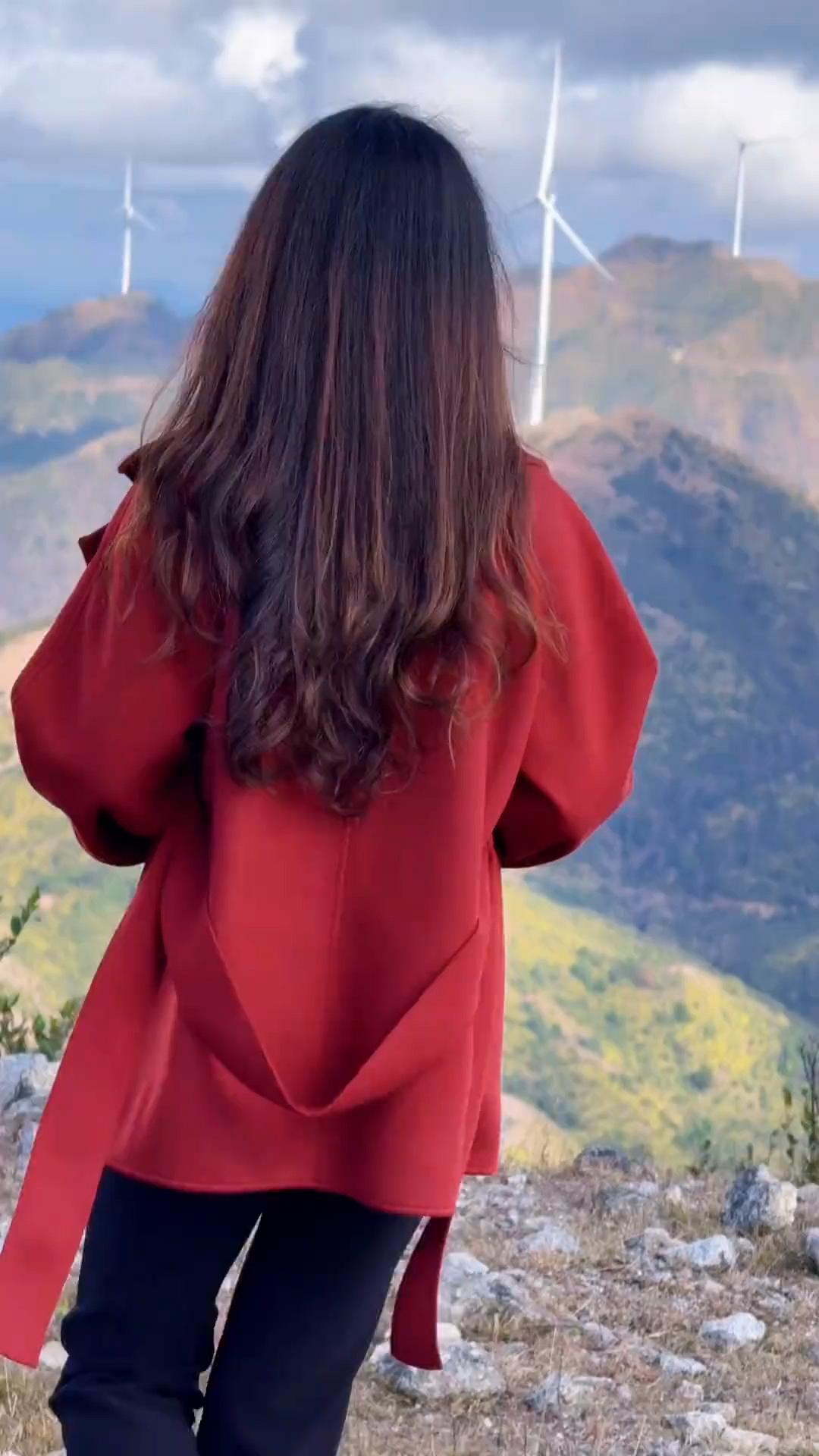 风车山上的红衣少女，背对镜头，看向远方。