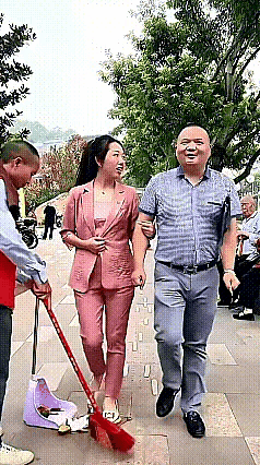 一对中年夫妻走在路上，此时环卫工人正在认真清扫路面，不小心扫到了妻子的脚面。只见