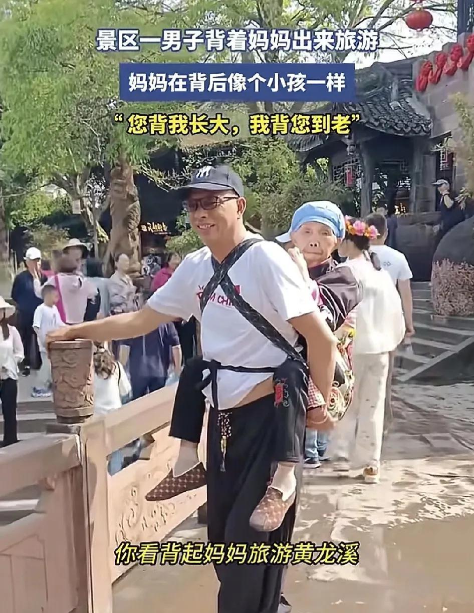 5月1日，四川黄龙溪景区那一名男子用背带背着自己的母亲游玩，这时的母亲就像一名小