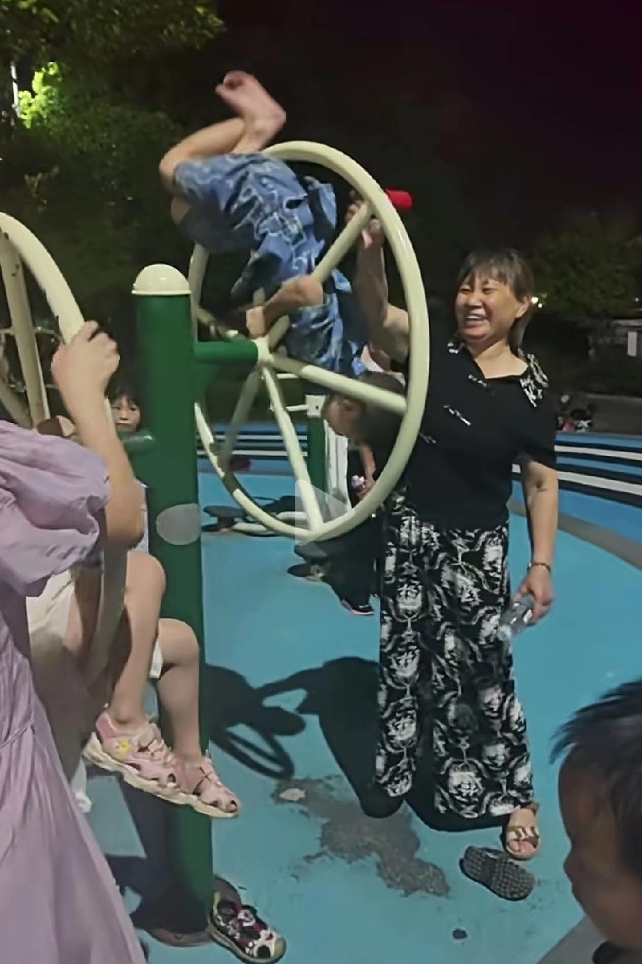 奶奶这样陪孙子玩太危险了！孙子双手抓住轮盘，奶奶则疯狂转动轮盘满脸喜笑，怎么就不