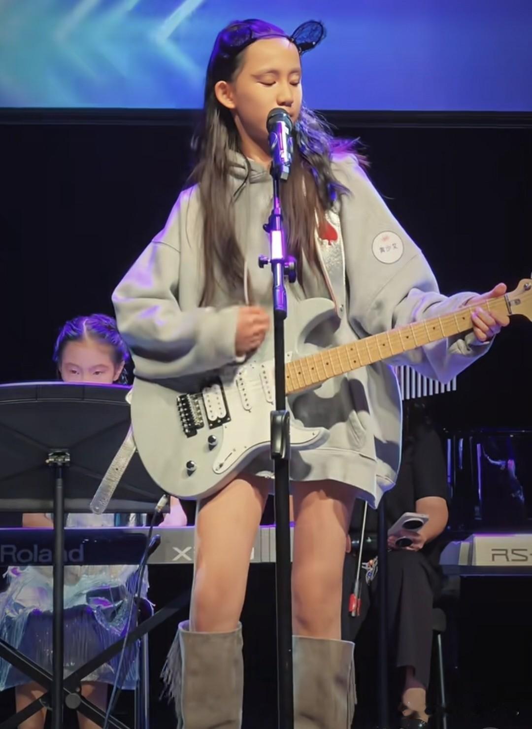 黄磊二女儿登台演出，12岁黄少艾穿长靴，披着长头发，手弹电吉他，又飒又酷，一家子文艺范，却养出来一位
