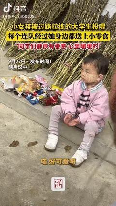 这画面挺暖的。陕西汉中，一个三岁小女孩在门口等奶奶，遇上一队拉练的大学生。学