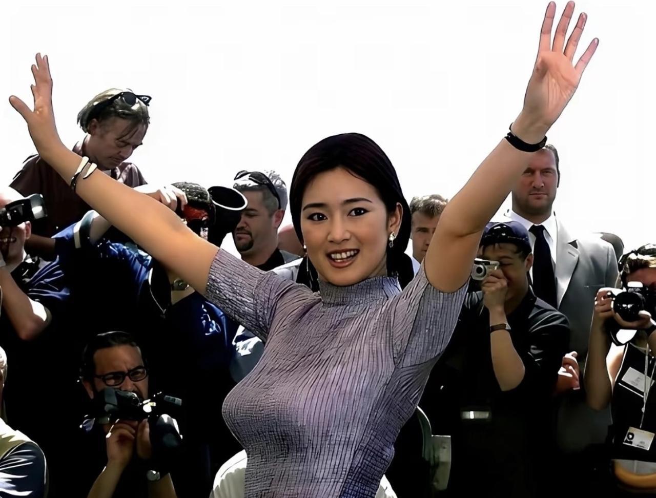 #老照片#国际影坛标志性人物巩俐，身着浅紫色修身针织上衣，双臂高举，笑容满面，