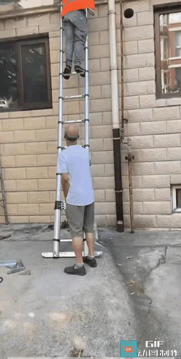 一名装修空调的师傅正站在梯子上修空调。一位路过的老人无缘无故抓着梯子使劲晃。眼看
