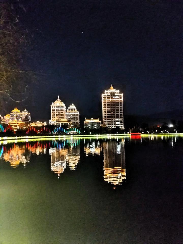 夜幕下的璀璨灯光，倒映在静谧湖面上，宛如梦境。沿着湖边小径漫步，脚下石板路在灯光