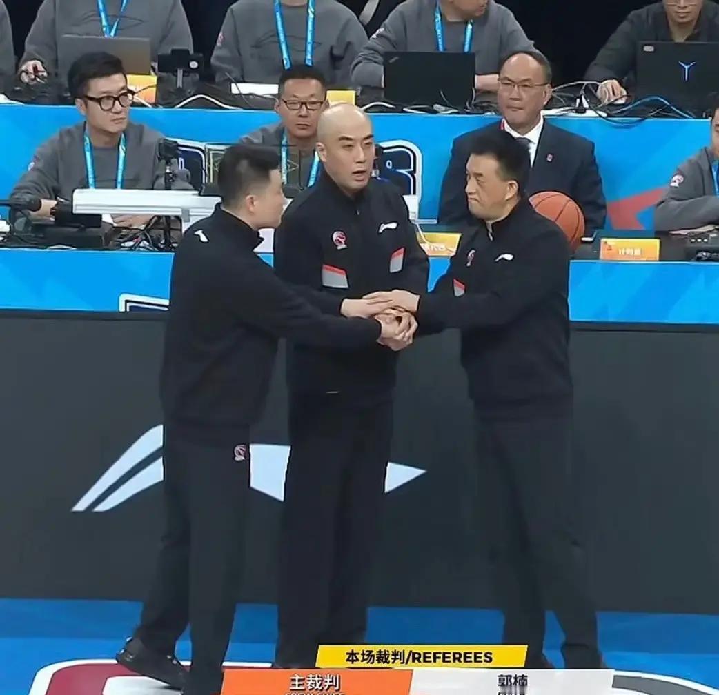 就在刚才，辽宁全队围堵裁判更衣室。镜头扫过技术台，99号裁判低着头快速离场。