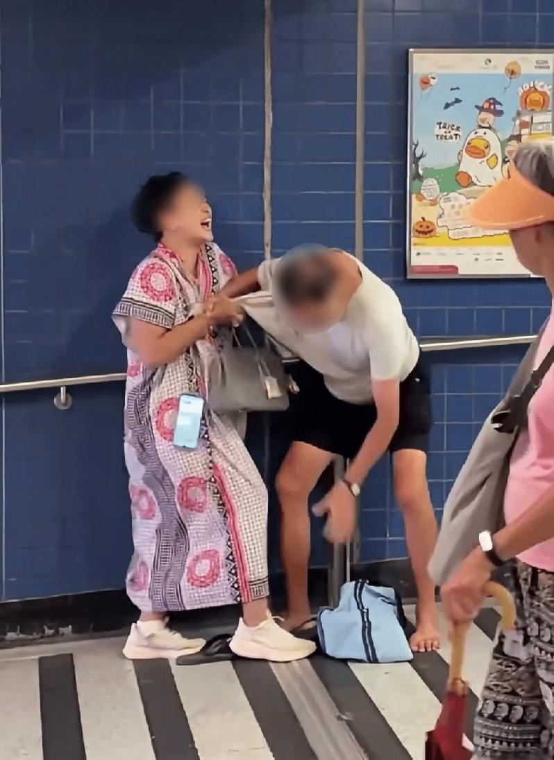 9月20日，香港港铁大围站A出口，一名中年妇人死死缠住一名赤脚阿伯，两个人在马路