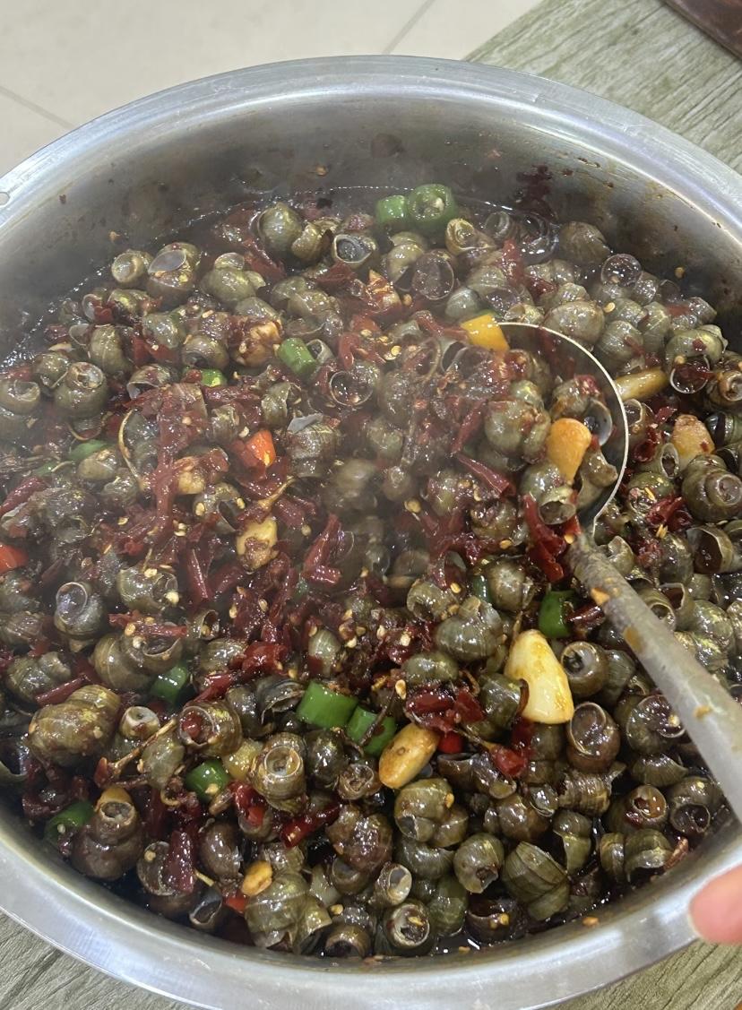 夜市一到，谁也躲不开那盘香气扑鼻的炒田螺。旺火下锅，干辣椒、花椒与蒜末瞬间爆香，