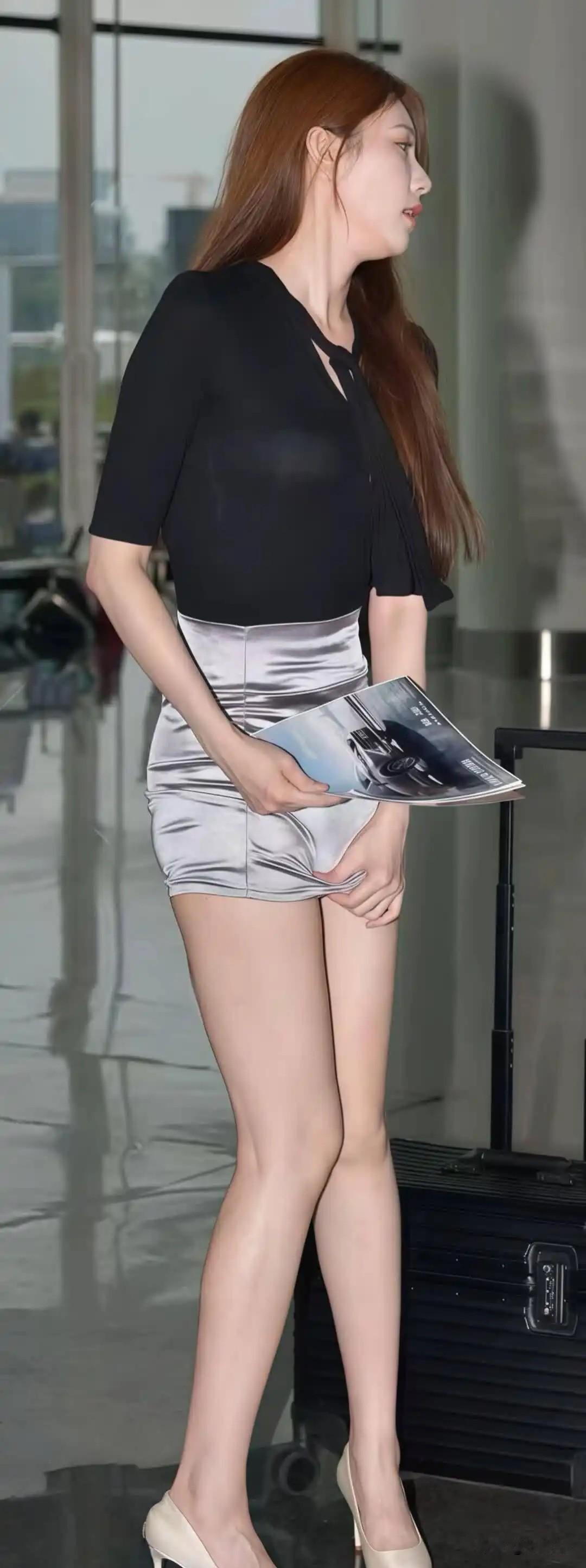 长发美女拖着行李箱，穿着闪亮短裙。