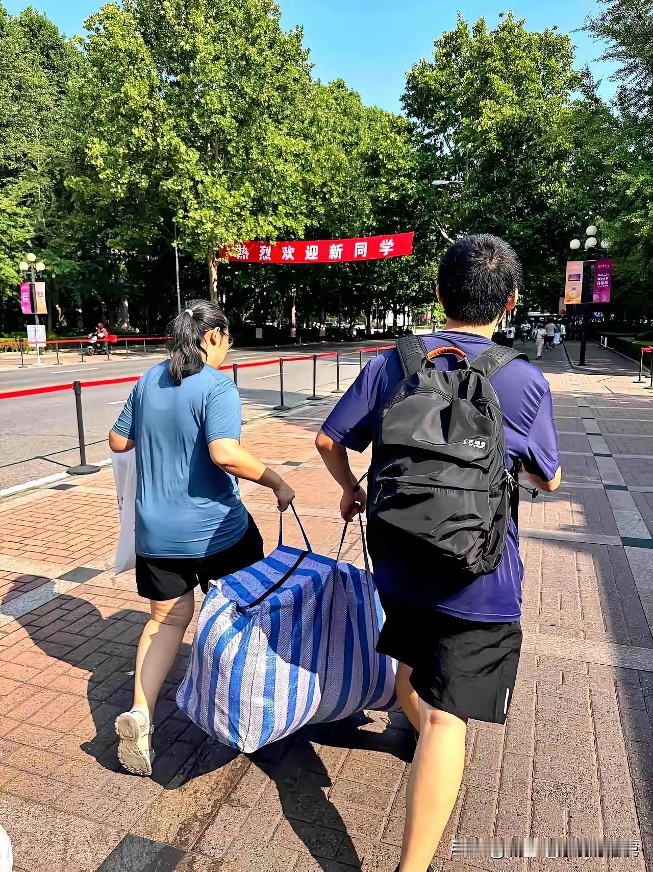立秋后的清华园，迎来2026级新生。人群中，一位新生和母亲抬着破旧蛇皮袋的画面格