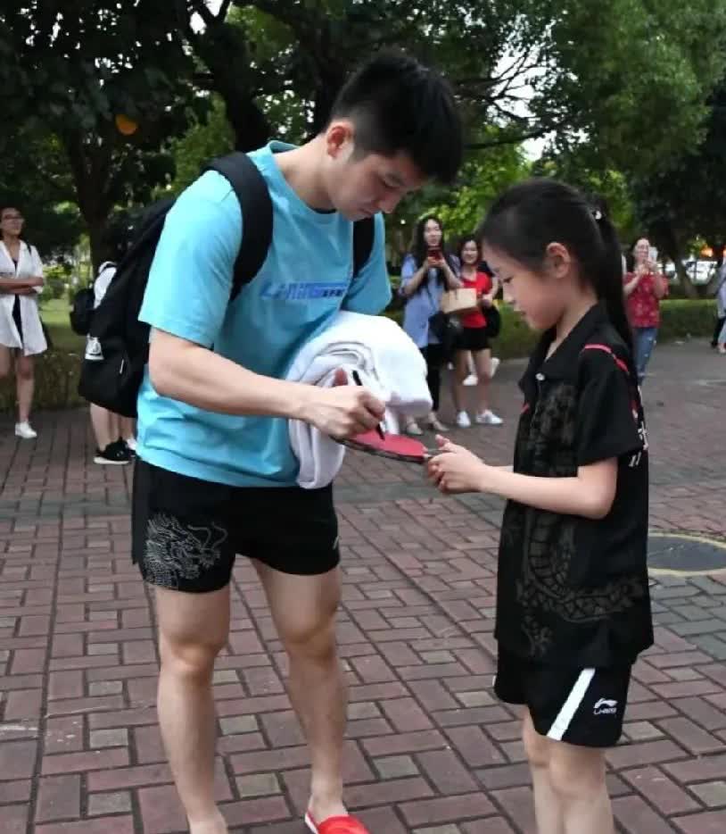 偶遇樊振东啦！他背着黑色双肩包，穿蓝色上衣配红拖鞋，随性又惬意～小球迷幸运邂逅，