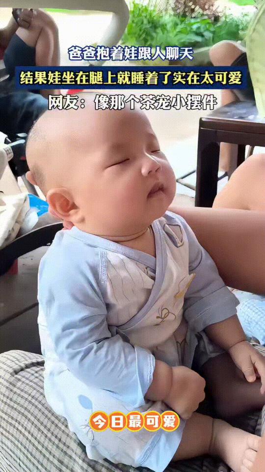 爸爸抱着宝宝跟人聊天，没想到宝宝坐在他腿上可睡着了，爸爸托着孩子的头，看着熟睡可