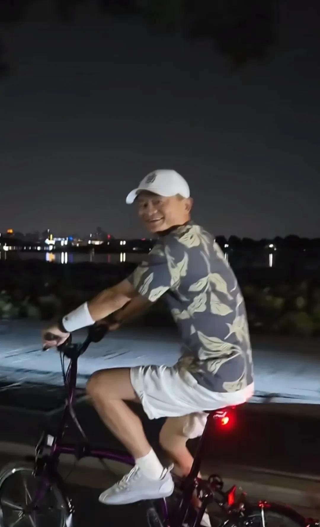 马云在西湖旁夜骑，头戴帽子，身穿迷彩短袖，白色短裤。网友问他可以拍吗？马云则没